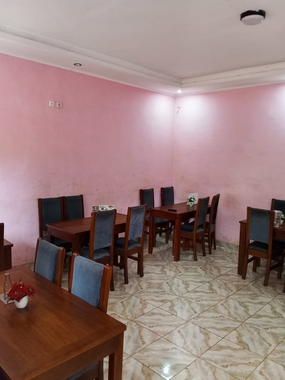Salle du restaurant aux murs roses avec tables et chaises en bois